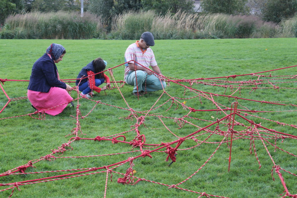 man woman child grass rope 